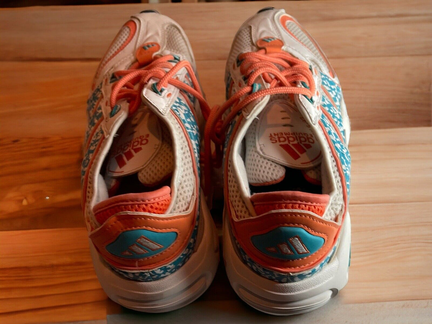 Top view of Adidas Originals FYW S-97 sneakers with orange and blue accents on a wooden surface