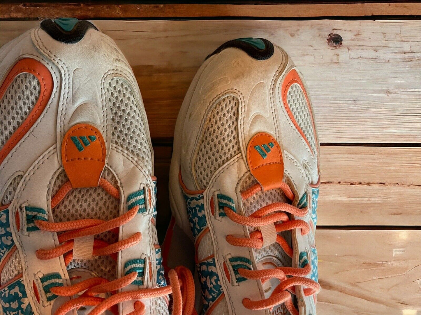 Top view of Adidas Originals FYW S-97 sneakers in white orange and teal on wooden floor