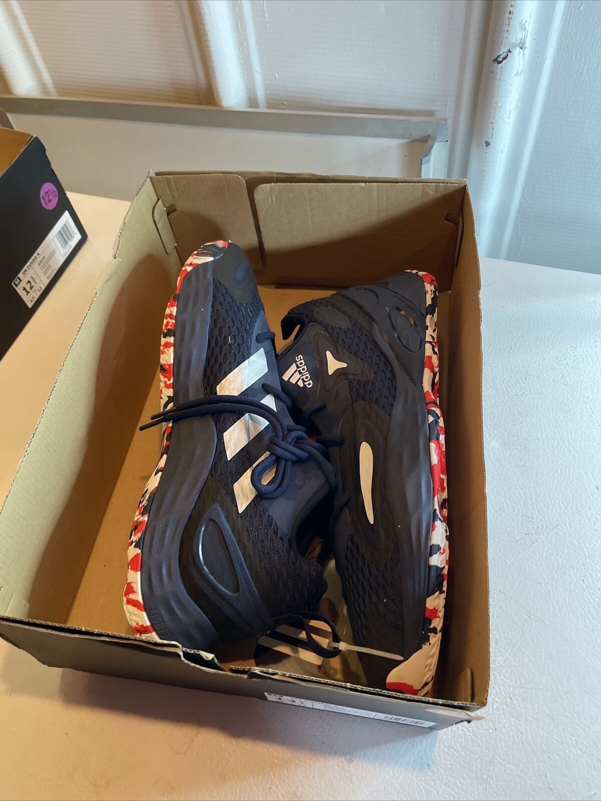 Adidas SM Exhibit A Team USA shoes in black with red and white patterned soles inside a cardboard box