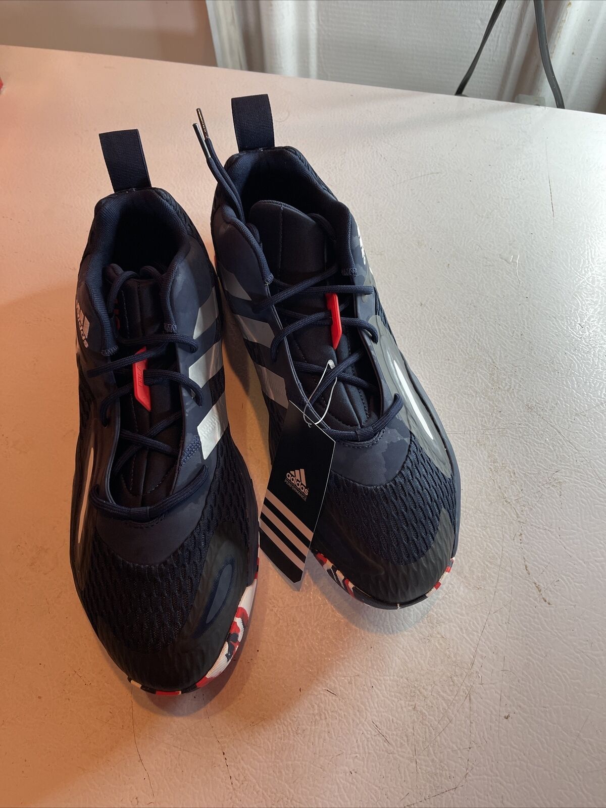 Adidas SM Exhibit A Team USA black athletic shoes with white stripes and red accents displayed on table