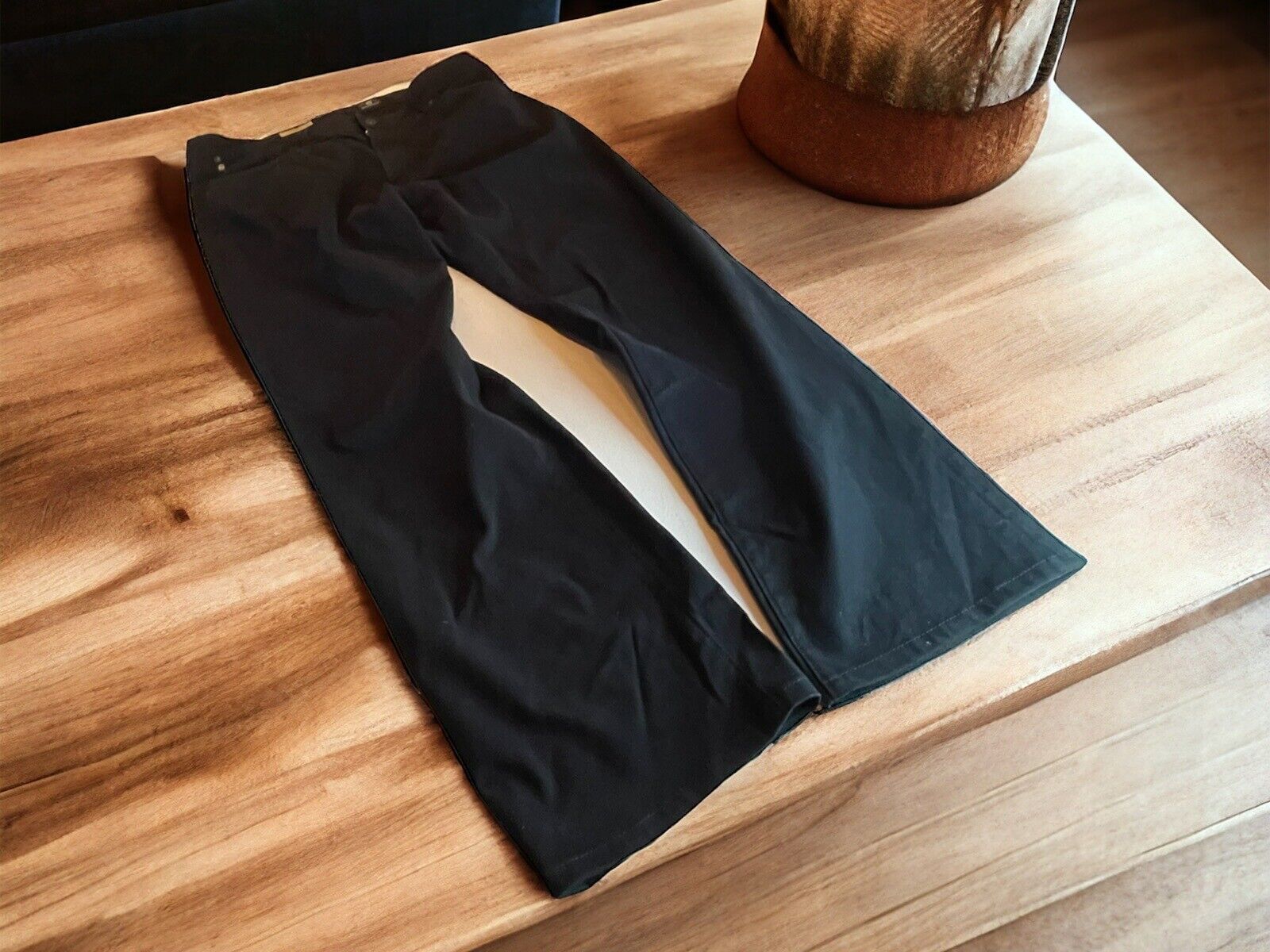 Adriano Goldschmied The Protege jeans laid flat on a wooden surface near a rustic decor item