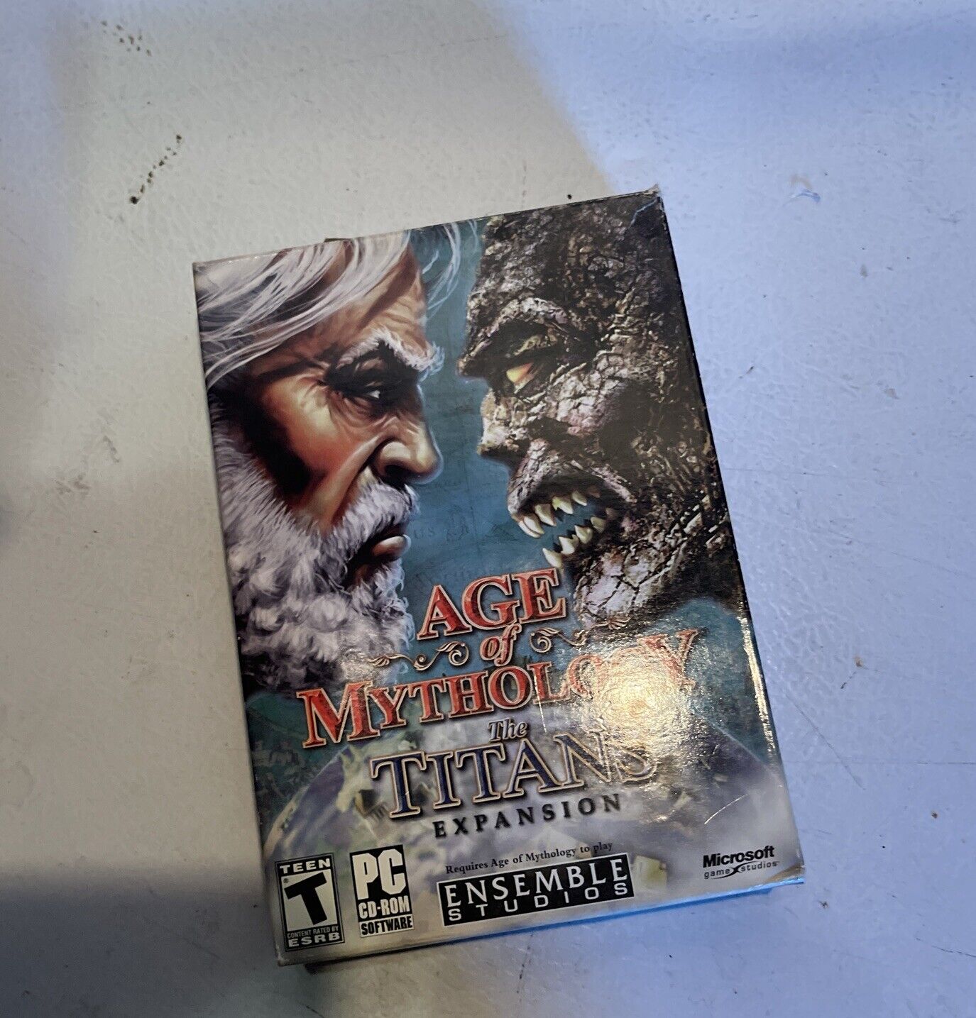 Age of Mythology Titans expansion PC game box featuring artwork of an old man and a stone titan face to face