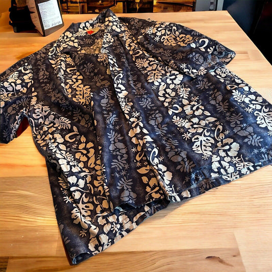 Black and white floral Ali’i Hawaiian shirt for men laid flat on wooden surface