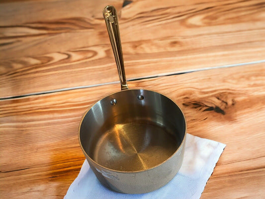 All Clad 3 quart saucepan stainless steel with long handle on wooden surface