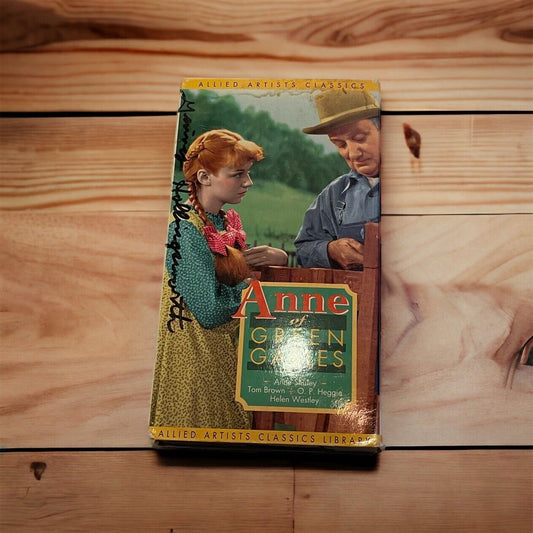 Anne of Green Gables VHS cover featuring Anne with red hair and a man in a hat on a wooden surface