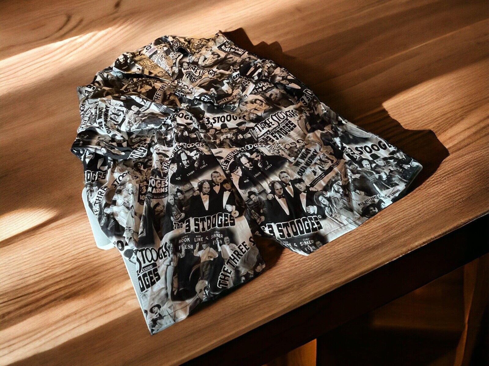 Alohaland all over print shirt with black and white graphic collage design on wooden surface