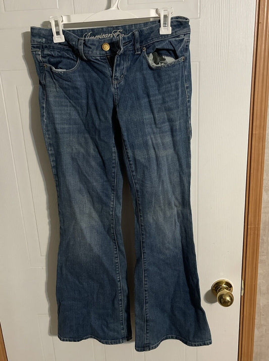 Blue denim American Eagle flare jeans hanging on white hanger against door