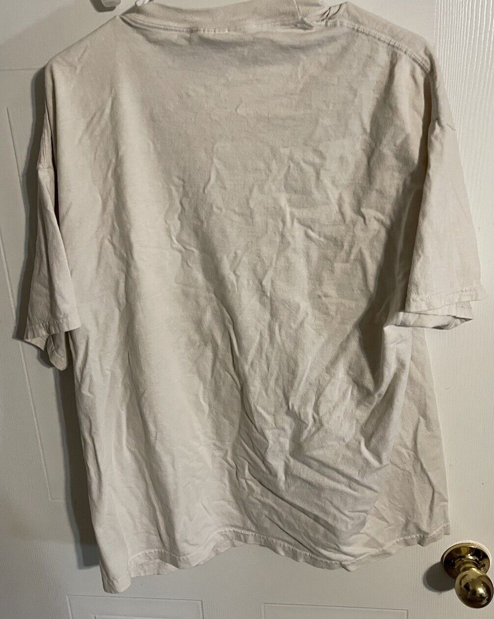 Plain light beige American steel biker t shirt hanging on door showing back side