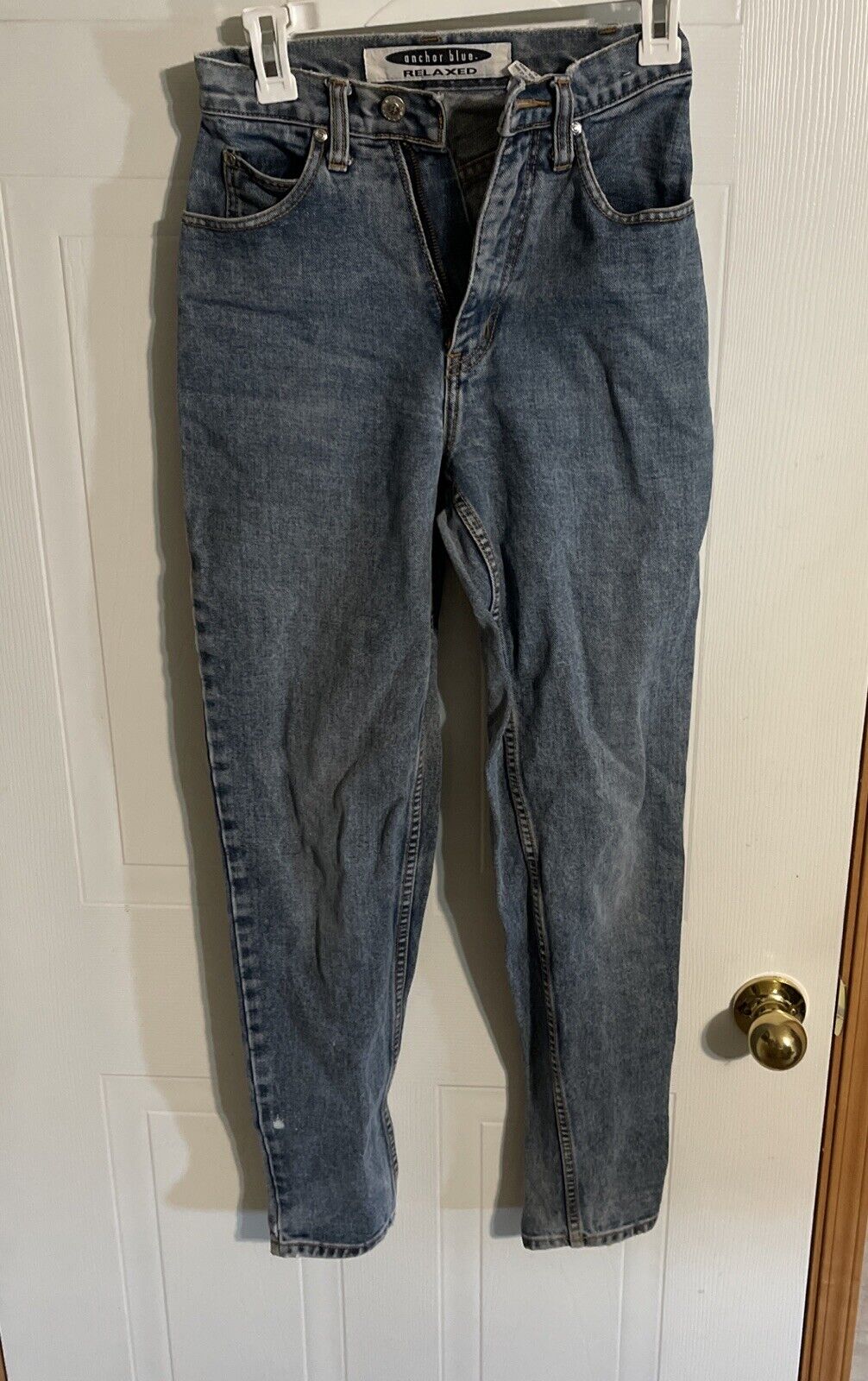 Anchor Blue relaxed fit jeans in classic blue denim hanging on white door