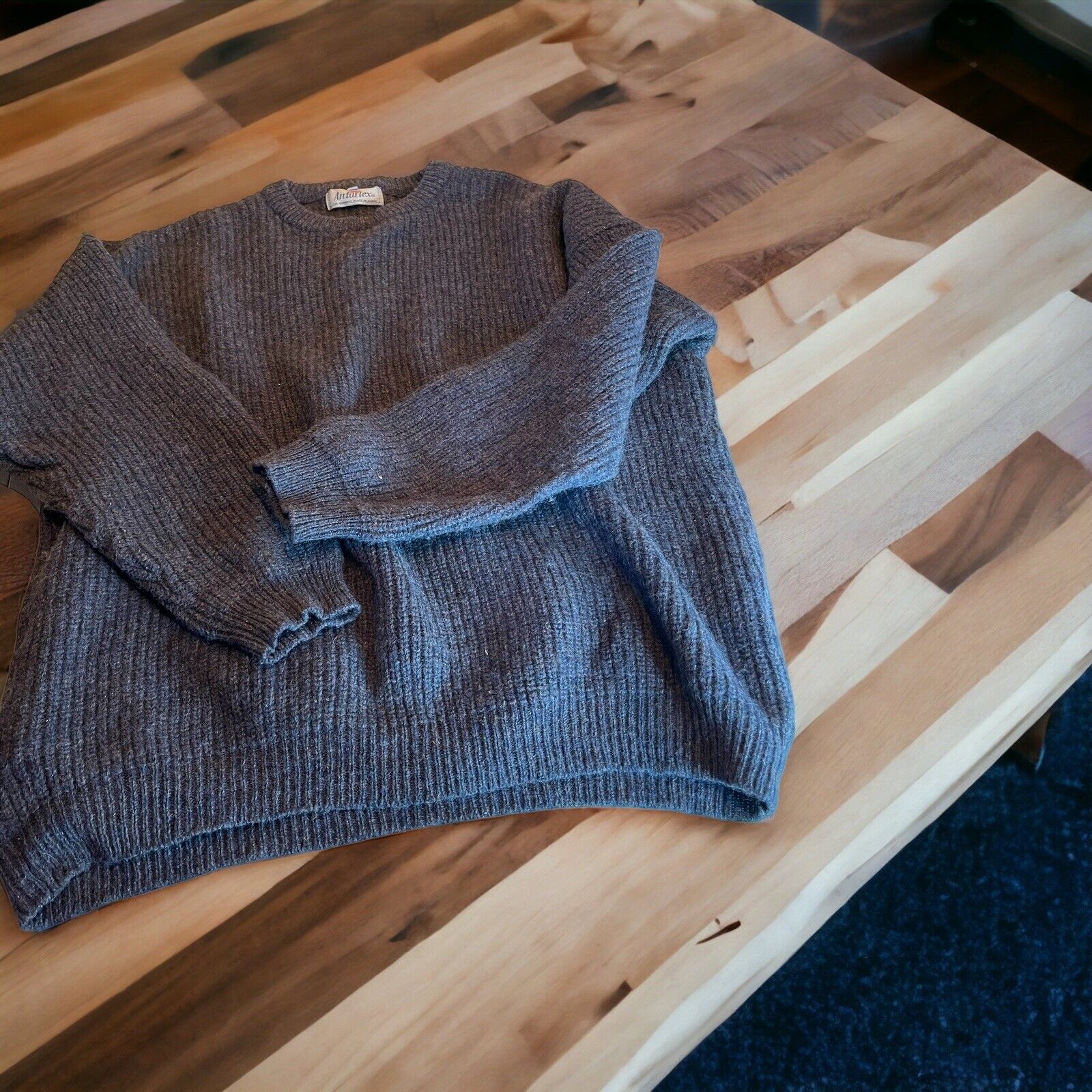 Gray Antartex wool sweater XL laid flat on wooden table showcasing ribbed texture and long sleeves