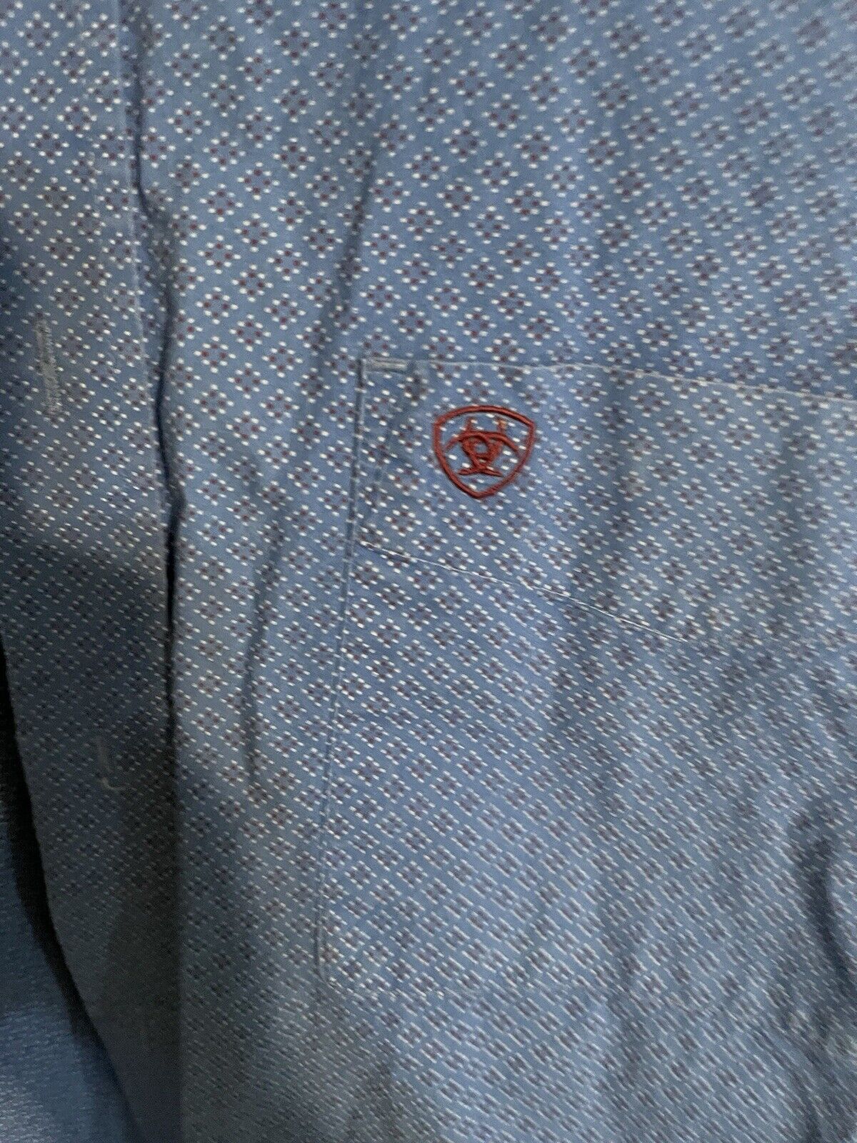 Close-up of Ariat blue button down shirt pocket with embroidered Ariat logo and blue patterned fabric