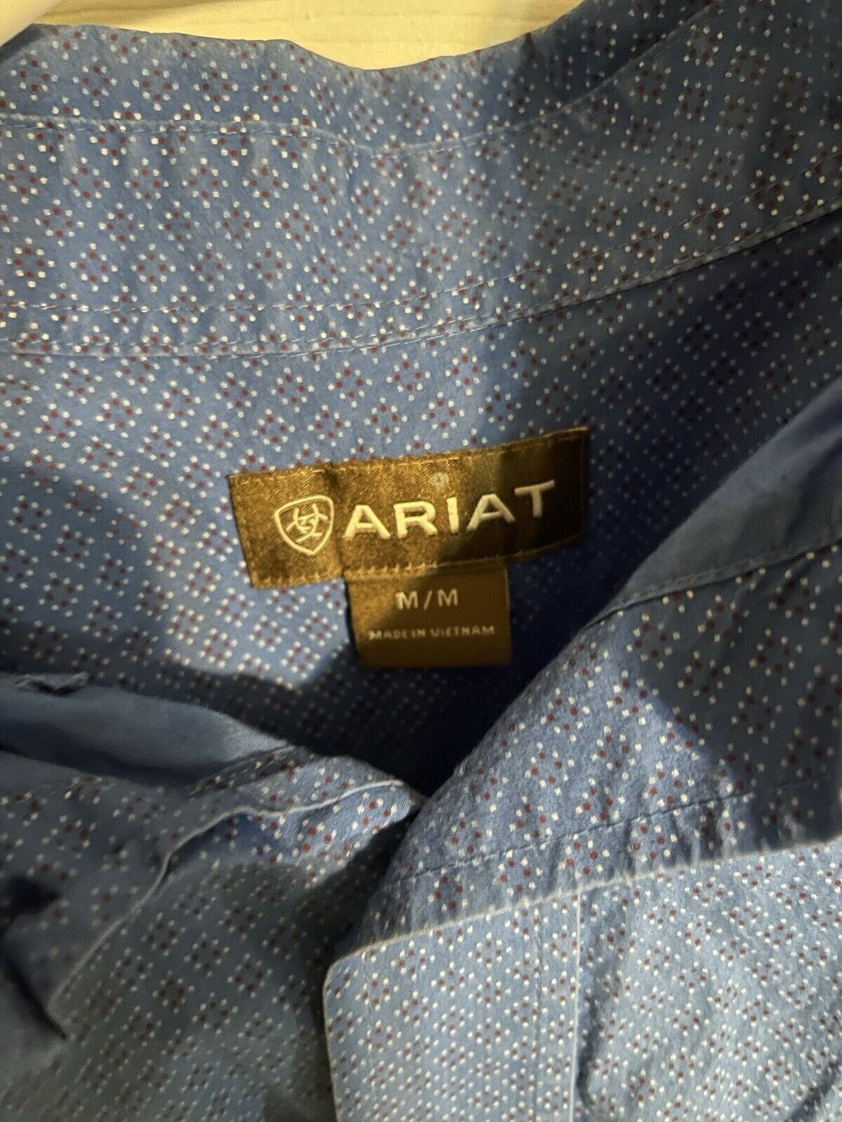 Close-up of Ariat label on Ariat blue button down shirt with patterned fabric in medium size