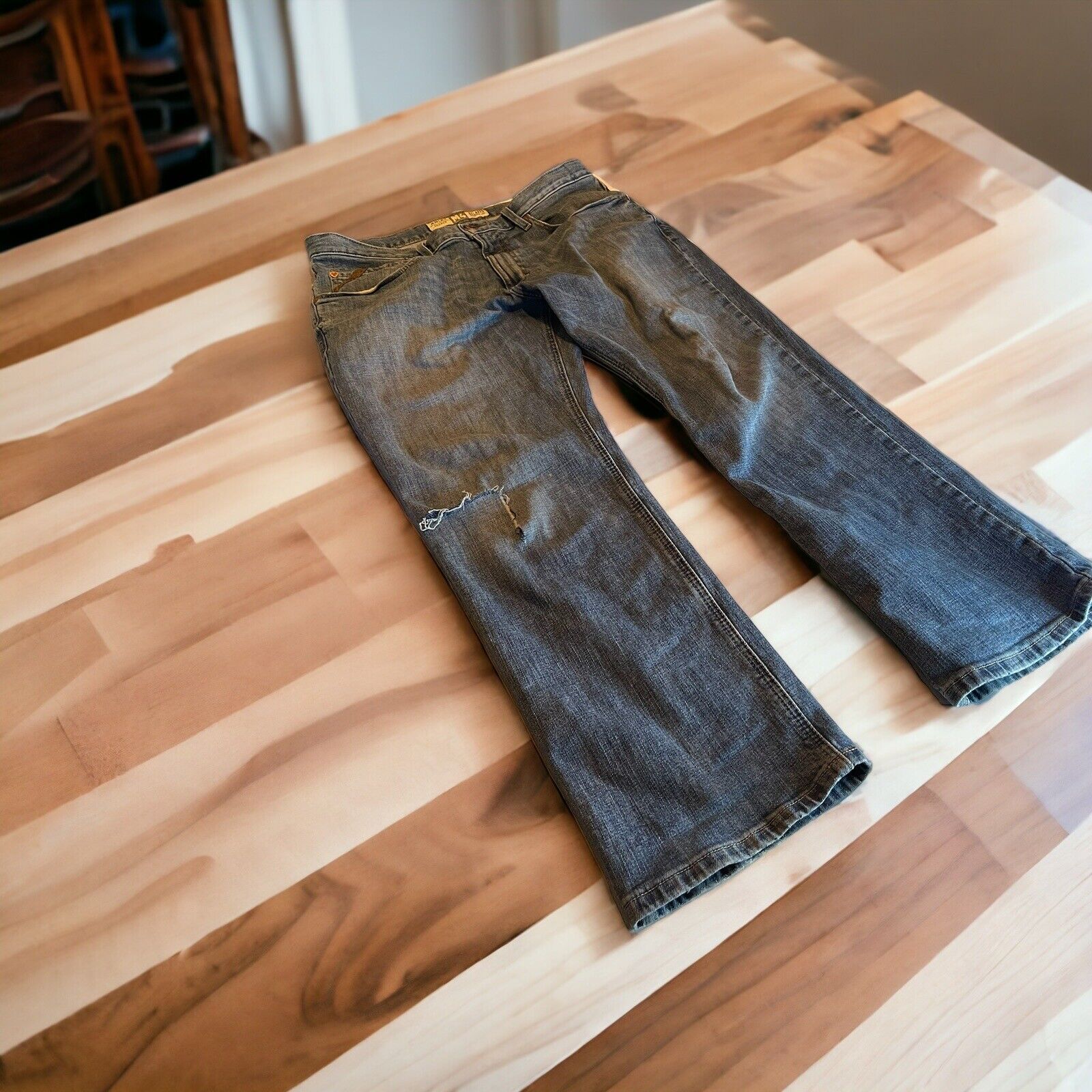 Ariat M4 Legacy jeans 35x30 in dark wash denim with slight distressing laid flat on wooden surface