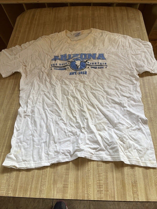 White Arizona tourist shirt XL with blue text and graphic laid flat on wooden surface