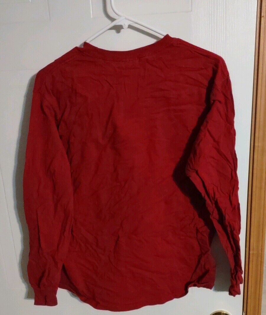 Red Arkansas Razorbacks long sleeve shirt hanging on white hanger against a white door