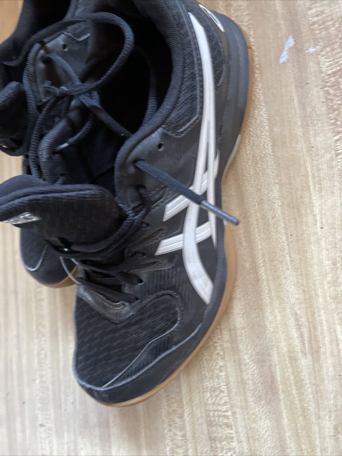 Black ASICS Gel Rocket size 9.5 basketball shoes with white logo and gum sole on wooden floor