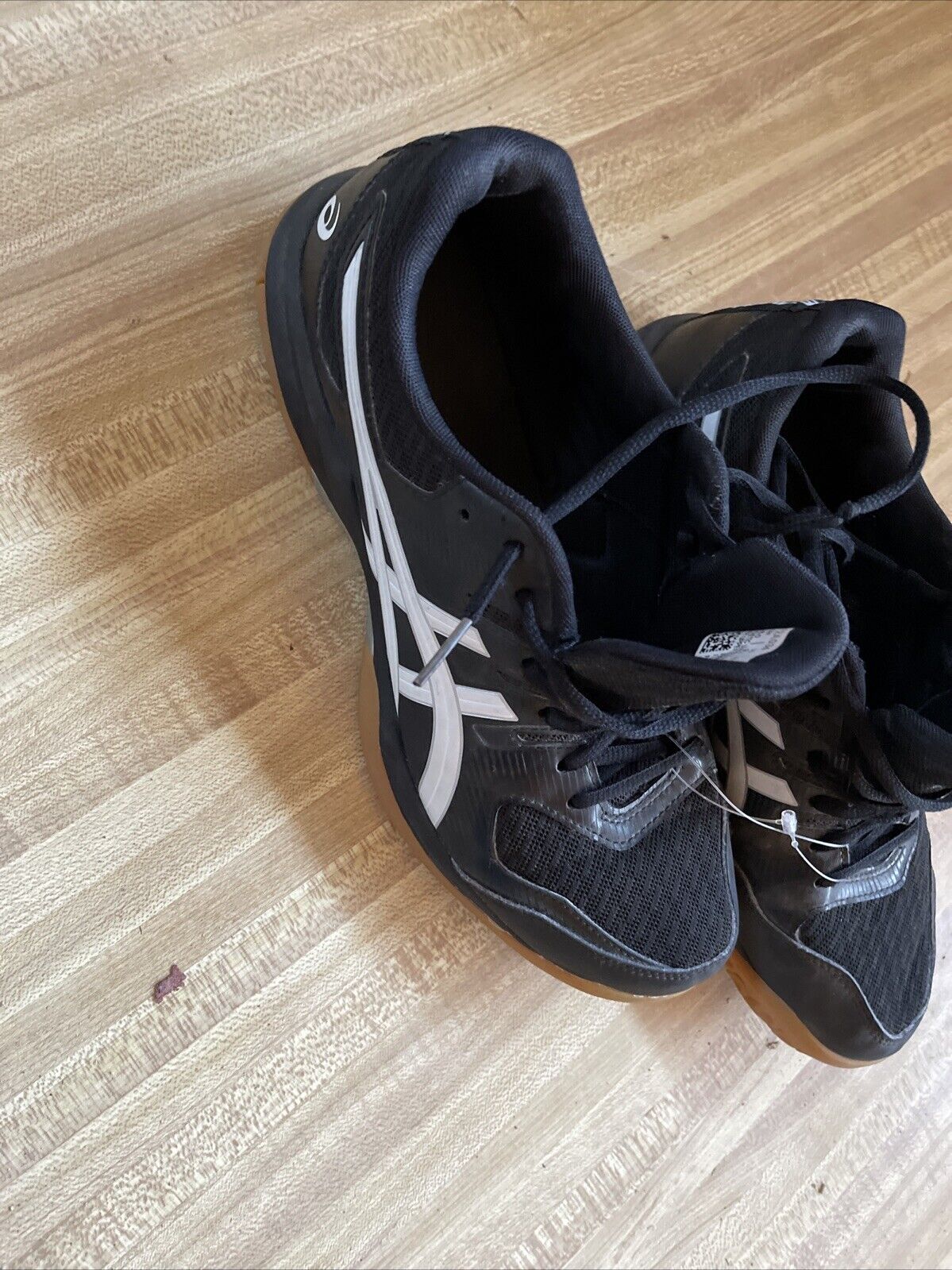 Black and white ASICS Gel Rocket size 9.5 basketball shoes on wooden floor