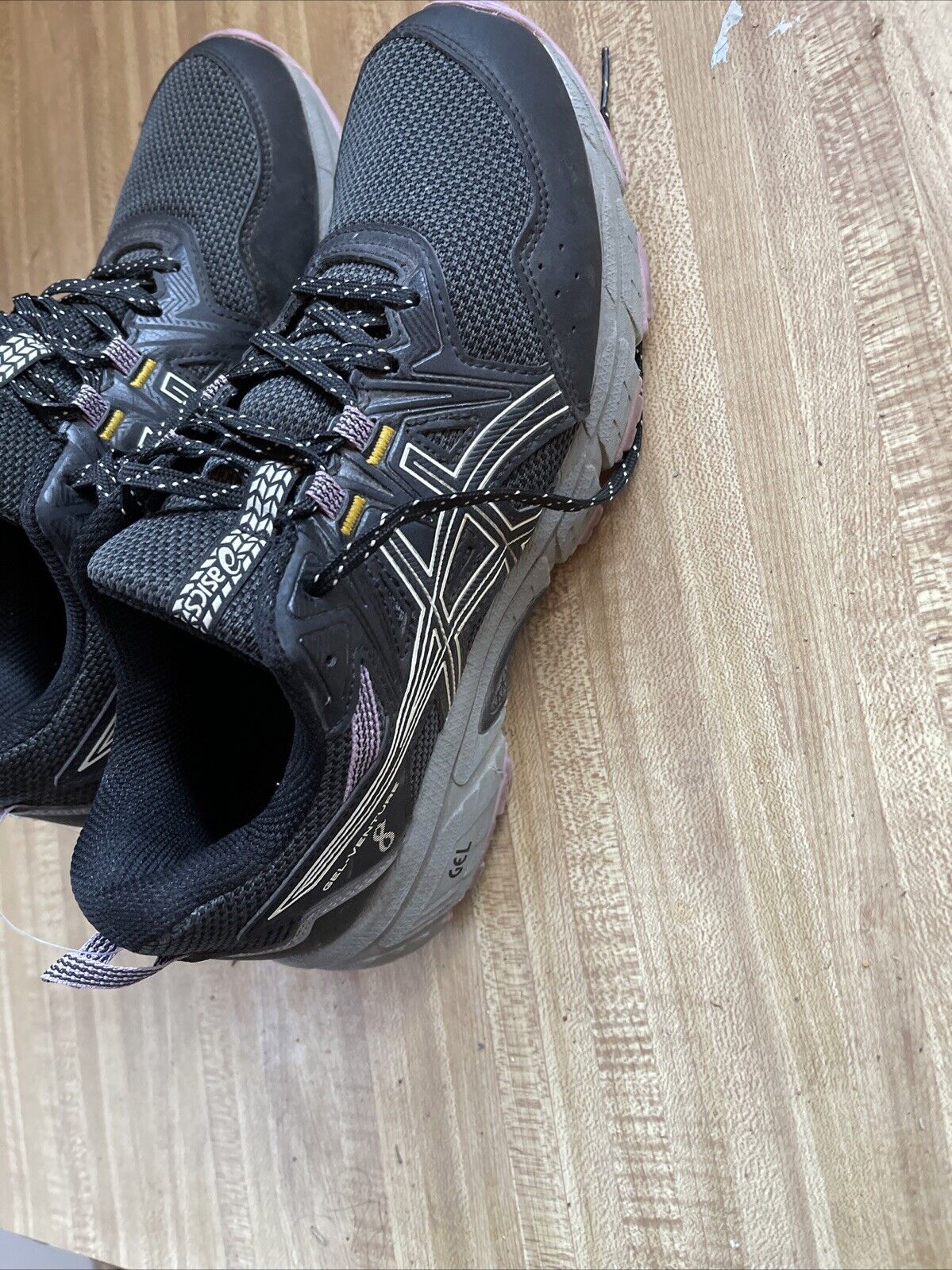 Black ASICS Gel Venture 8 women’s wide running shoes with cushioned sole on wooden floor