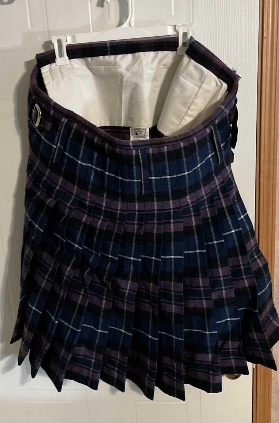 Purple and navy plaid Atlanta Kilts kilt for sale hanging on a white hanger with buckle straps