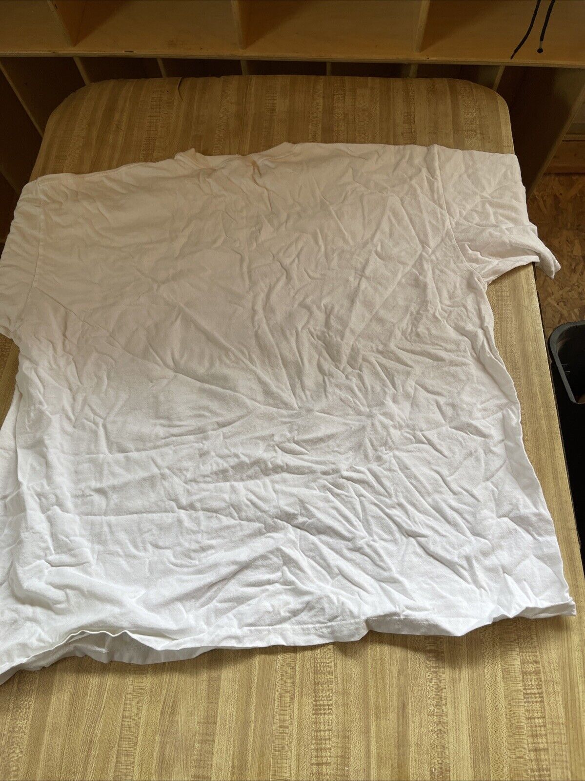 Wrinkled plain white Austin Dillon 3XL t shirt laid flat on wooden surface