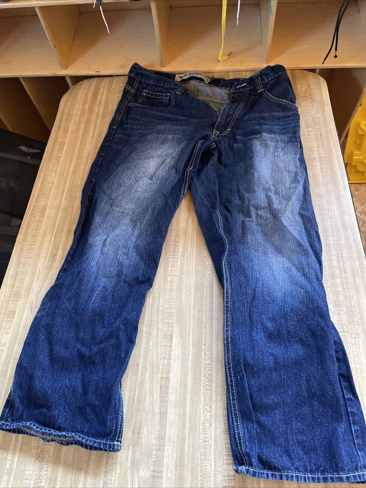Avirex jeans 34x30 in dark blue denim with faded areas laid flat on a beige surface