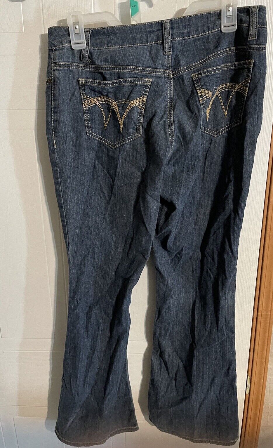 Back view of Baccini jeans 8P women in dark denim with stitched pocket design hanging on clip hanger