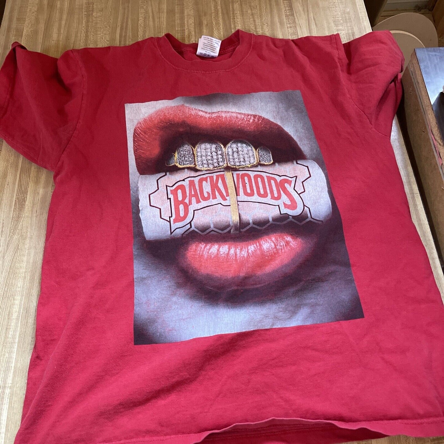 Red Backwoods Grill t-shirt featuring lips with gold teeth holding a Backwoods cigar pack