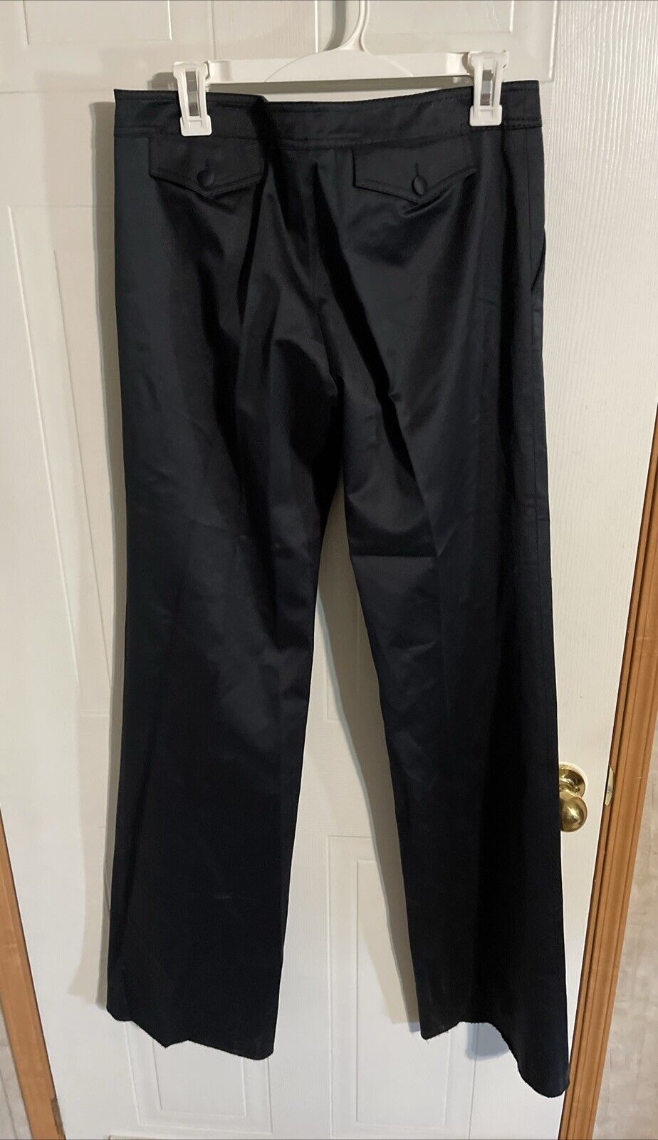 Bally black dress pants hanging on white hanger with buttoned back pockets