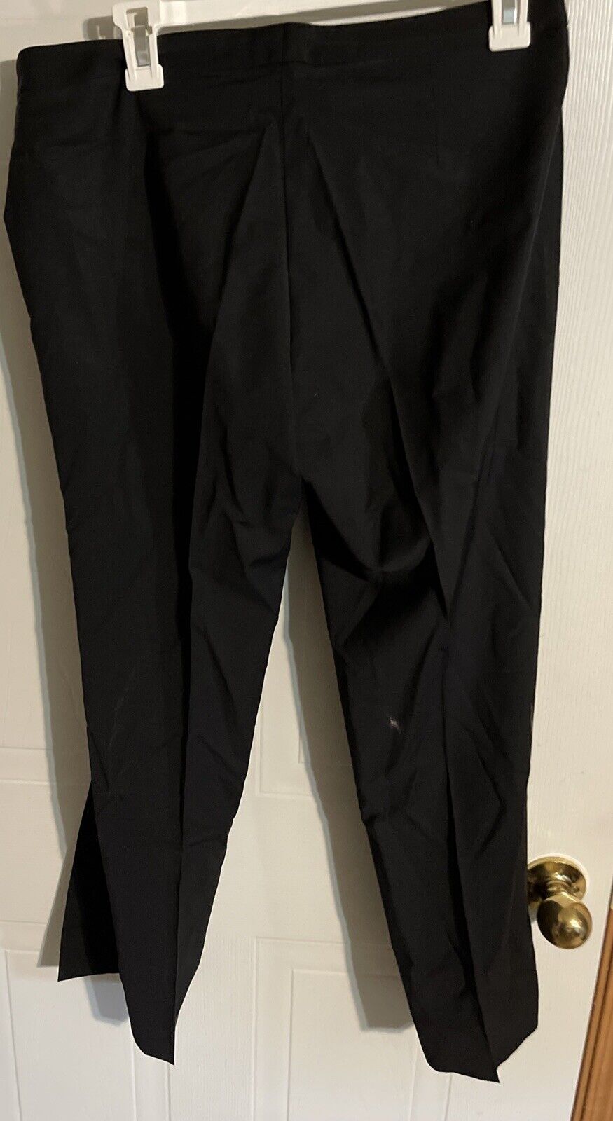 Bally black suit pants size 10 hanging on white hanger against white door