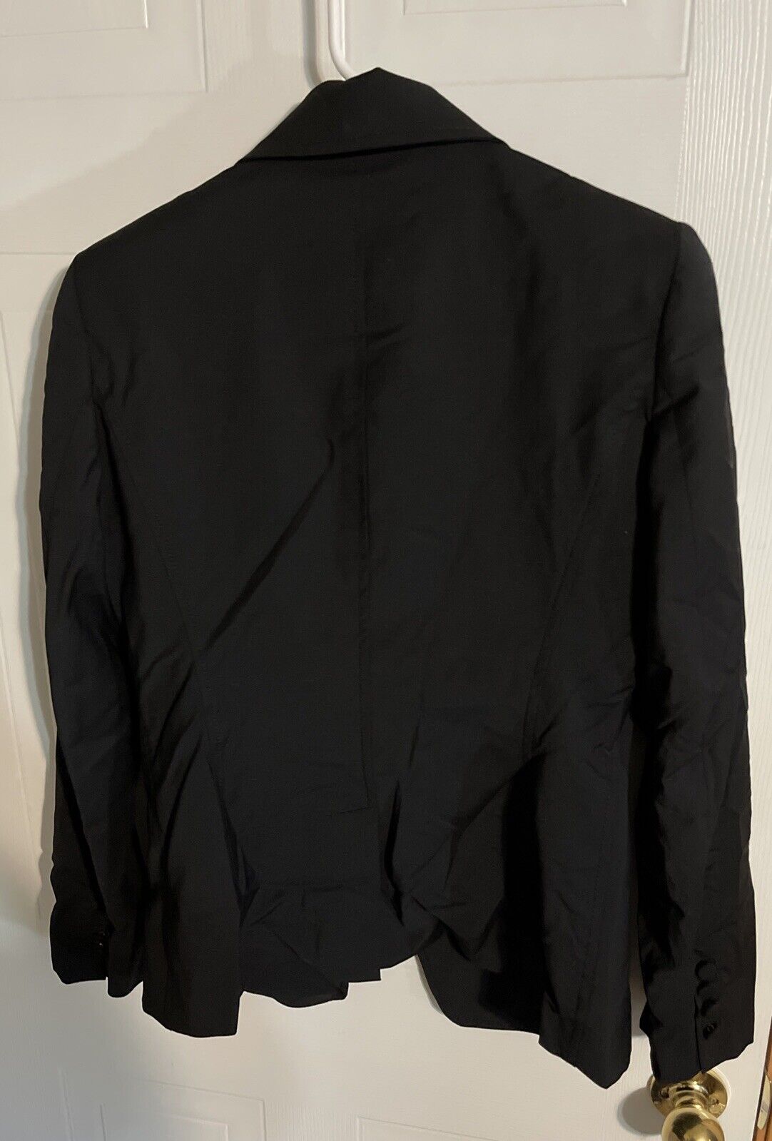 Back view of Bally black suit pants size 10 hanging on white door with visible wrinkles