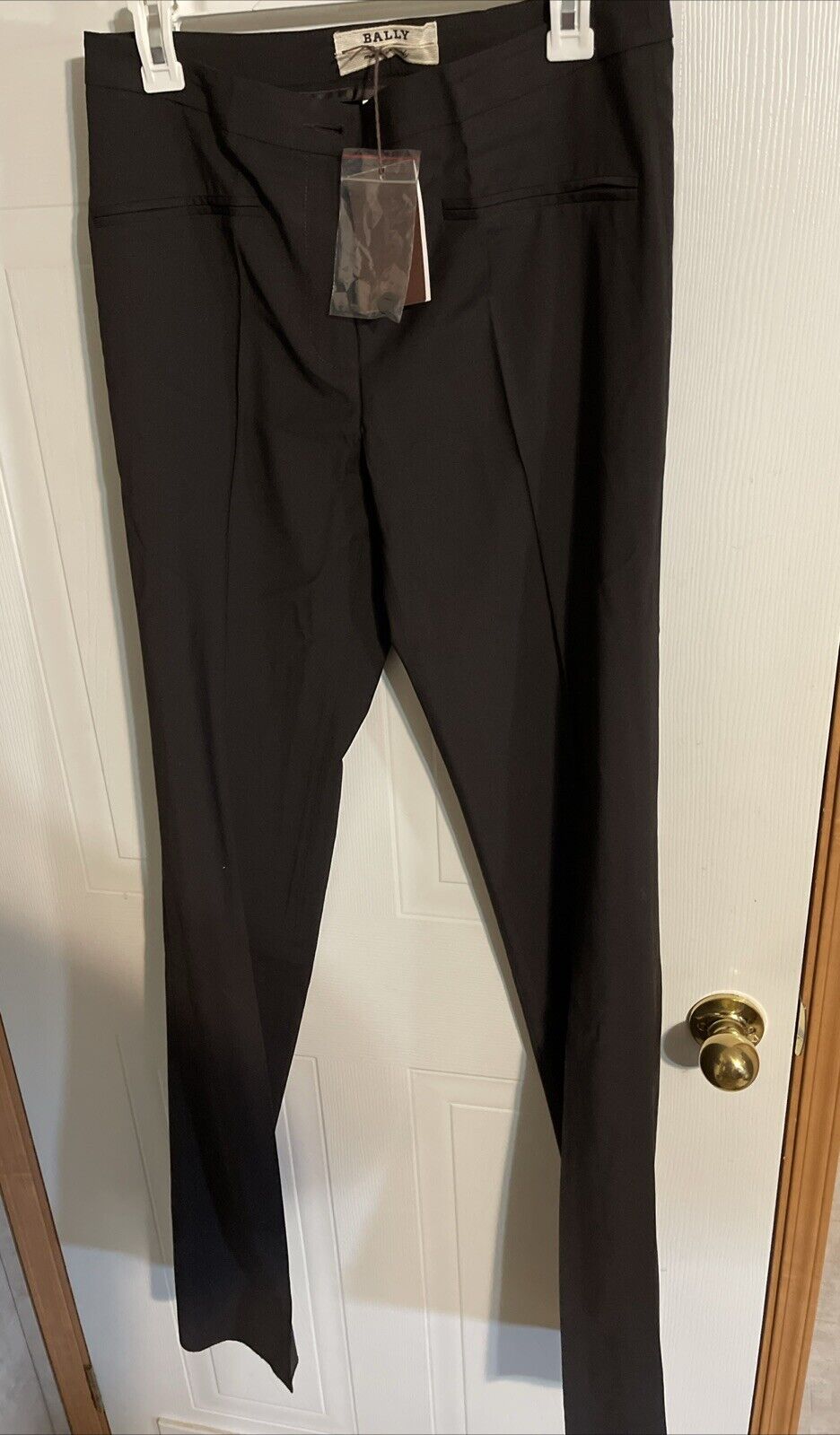 Black Bally dress pants for women hanging on a white door with tags attached