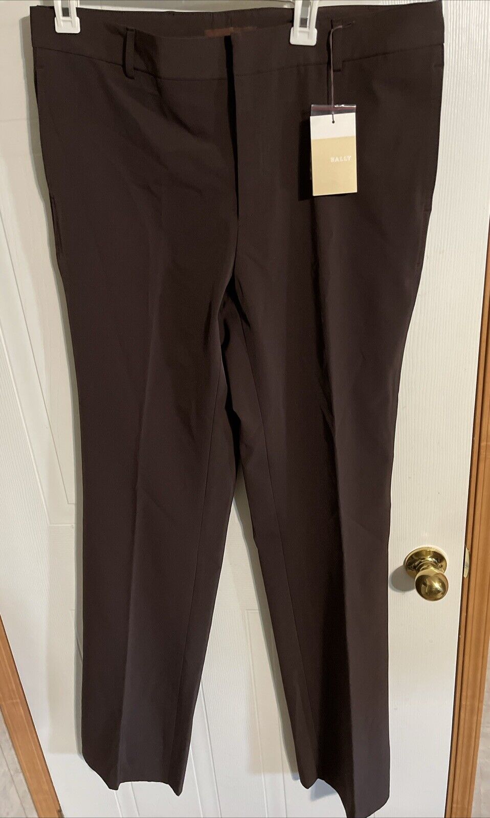 Bally men’s dress pants in dark brown hanging on white door with tag from 1118 Emporium