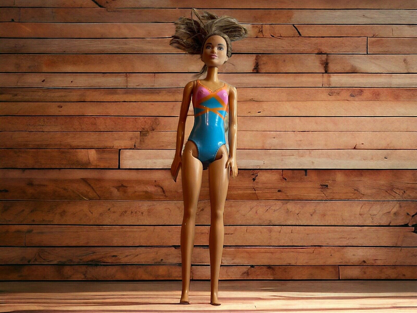 1118 Emporium Barbie beach doll wearing a colorful swimsuit standing against a wooden background