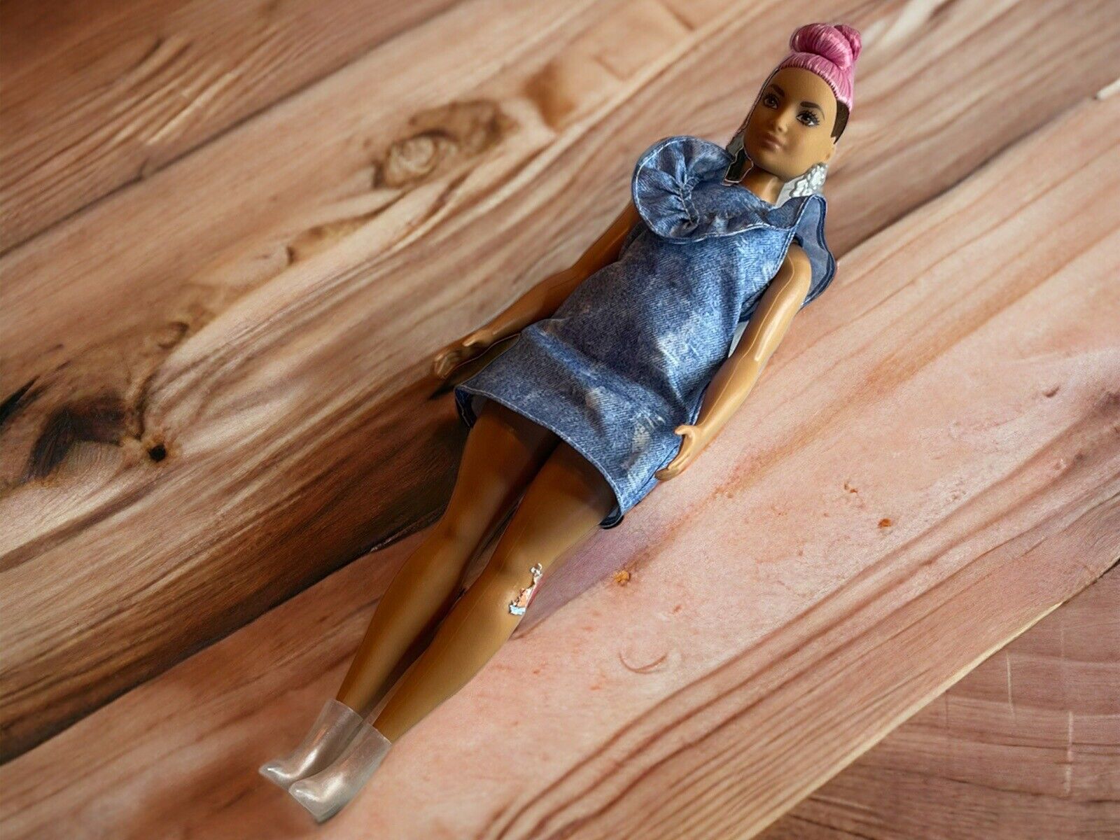 Barbie Fashionistas Doll with pink hair in a blue dress lying on a wooden surface