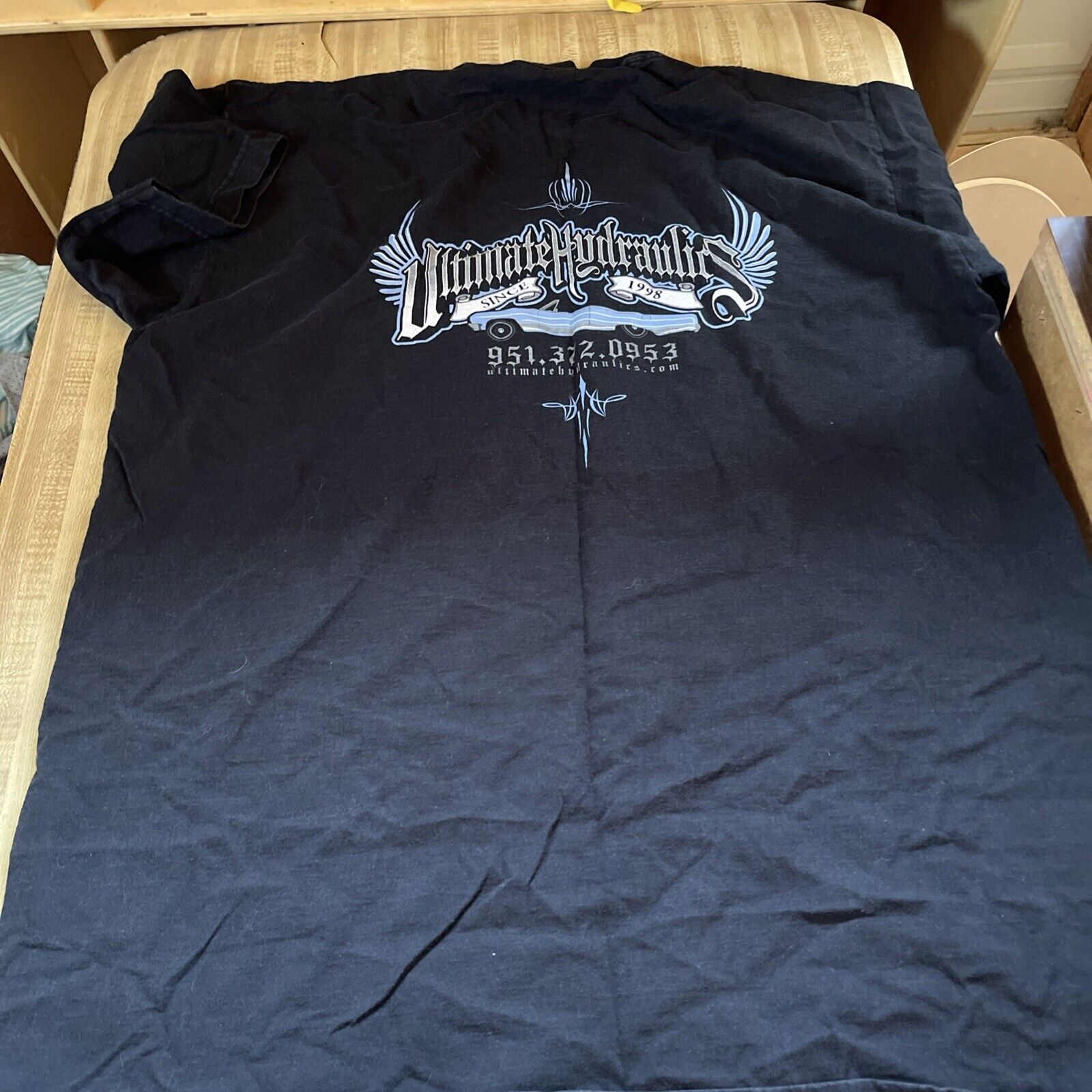 Black big and tall workwear t-shirt with white graphic text design laid flat on a beige surface