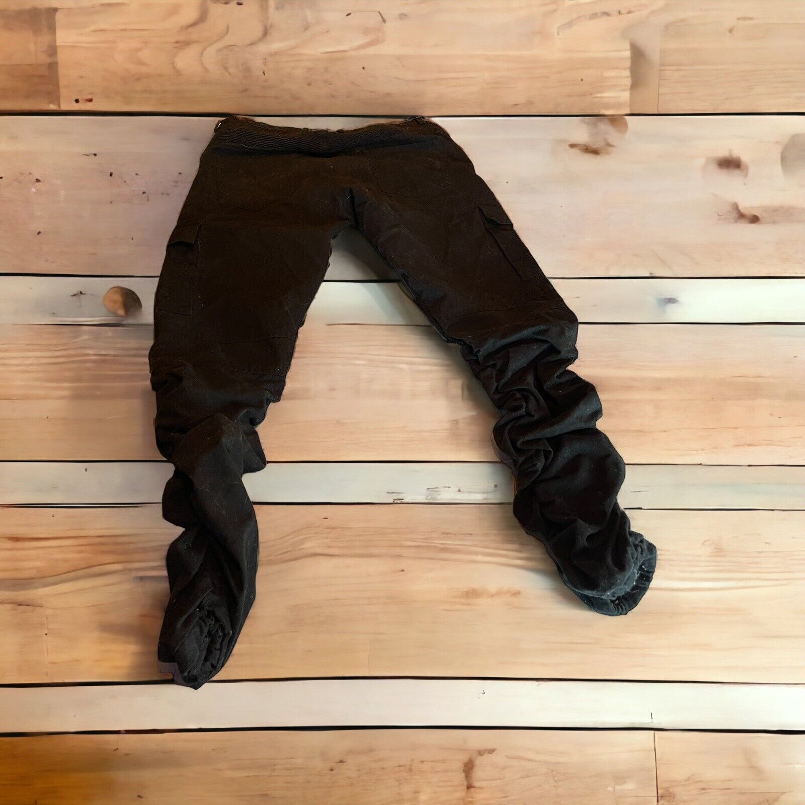 Black cargo pants with zipper pockets laid flat on wooden background from 1118 Emporium