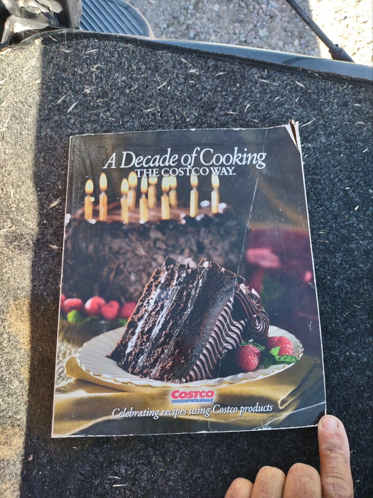 A Decade of Cooking The Costco Way cookbook featuring chocolate cake slice on white plate with strawberries, Costco cookbook