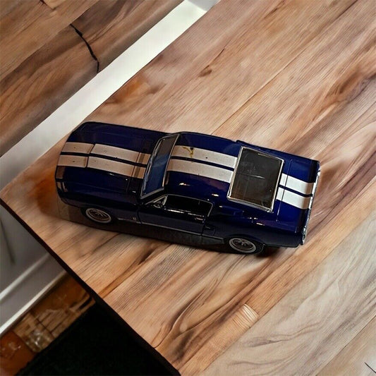 Blue diecast muscle car model with white racing stripes on wooden surface by 1118 Emporium