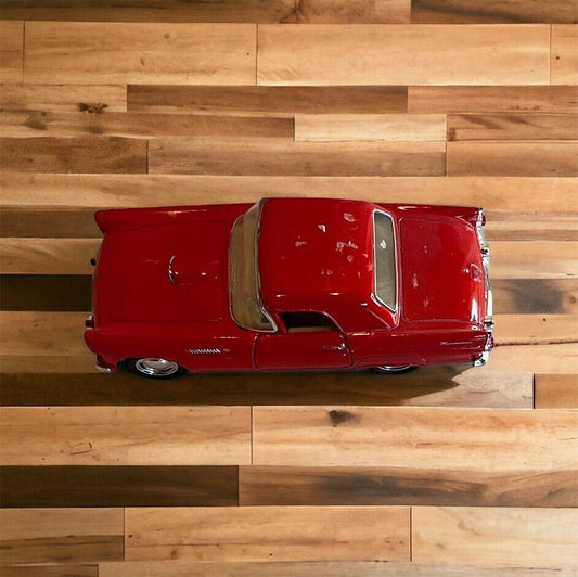 Red 1955 Thunderbird diecast model car viewed from above on wooden surface