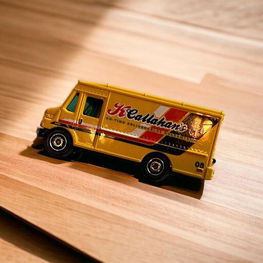 Yellow MBX Adventure City diecast collectible delivery van with detailed graphics on wooden surface
