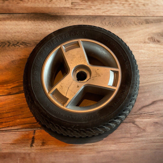 Powertrax wheel for carts with durable black rubber tire and three-spoke silver rim on wooden surface