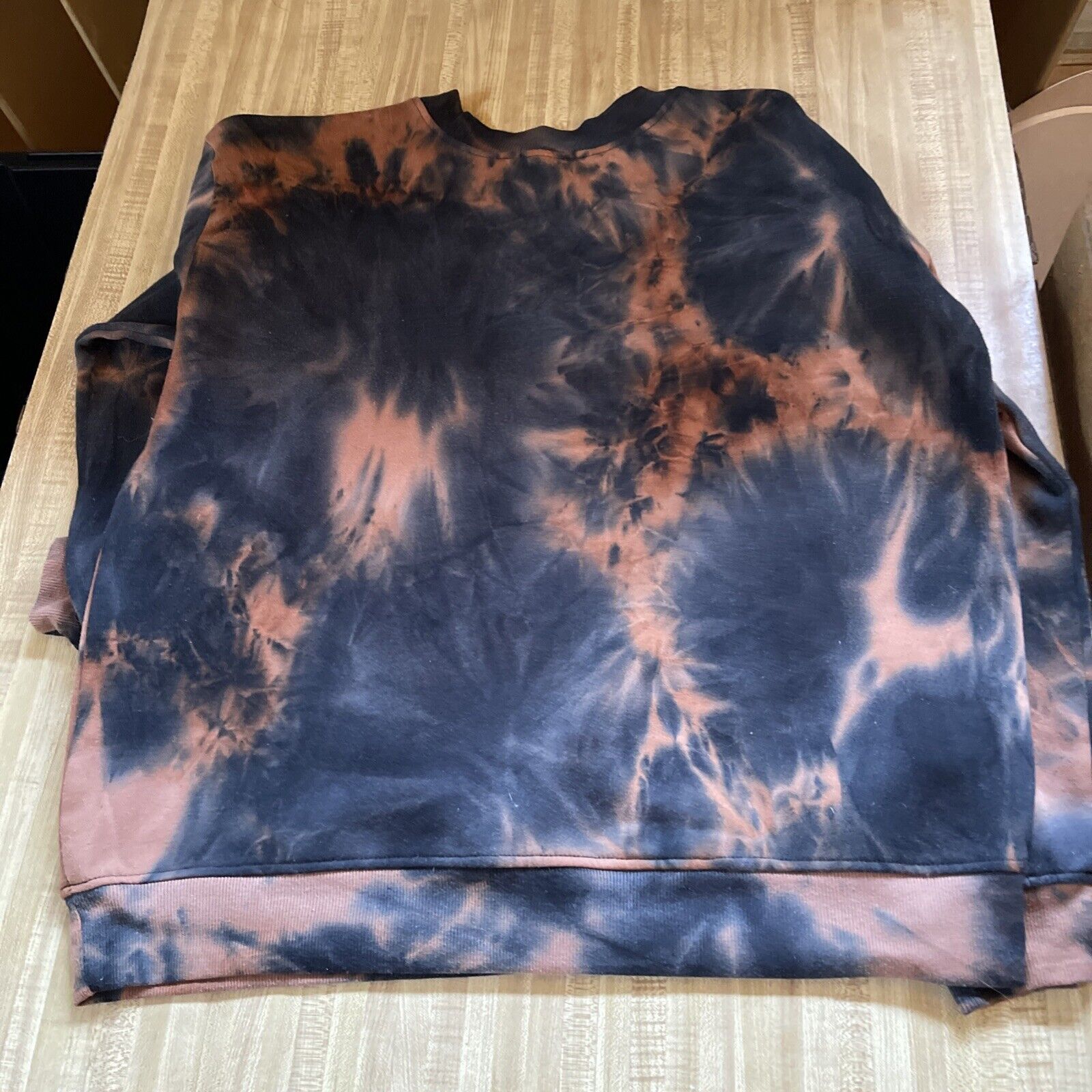 Tie dye black and orange Salem Massachusetts sweatshirt folded on wooden surface