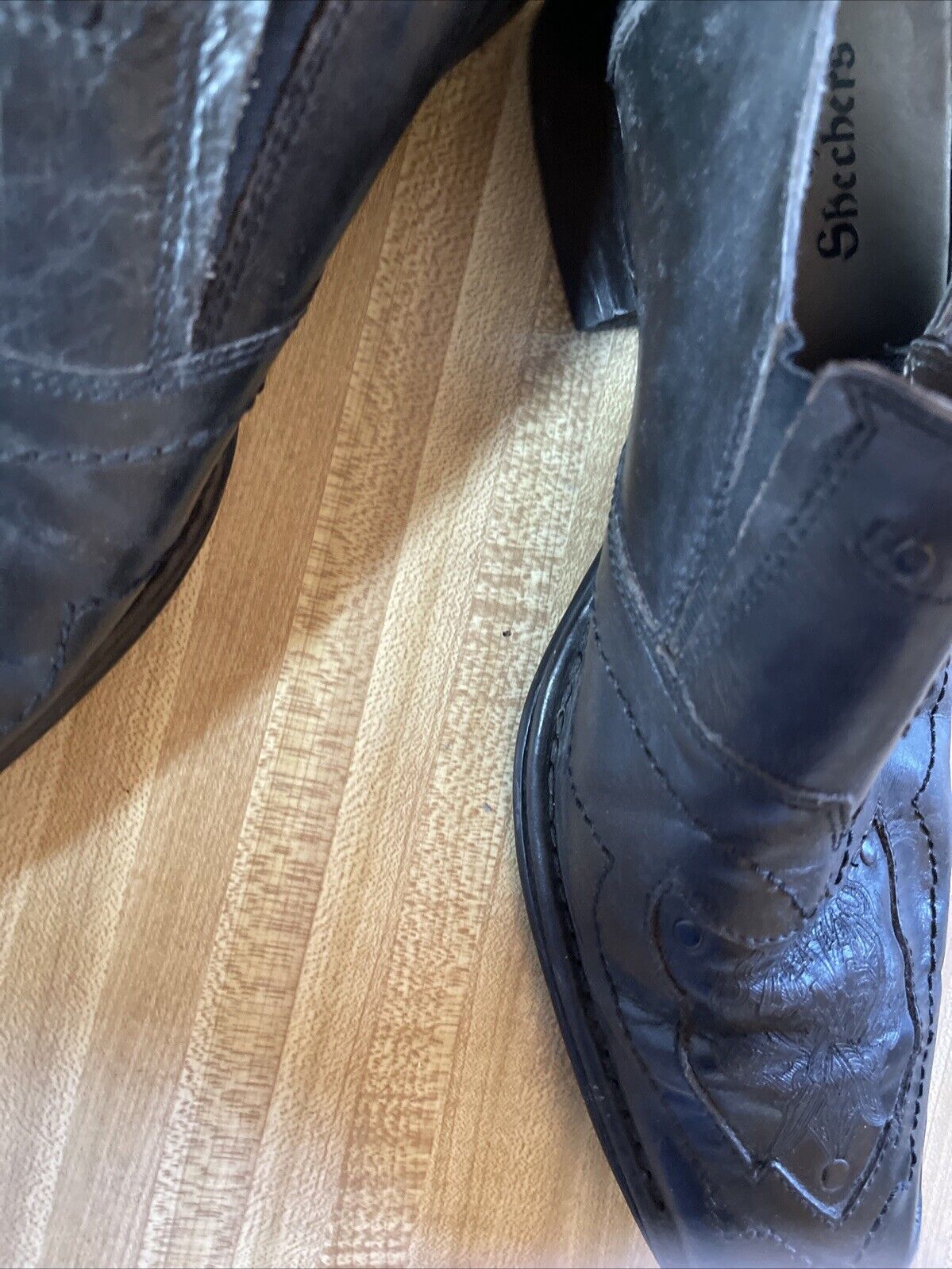 Black leather Back Stage by Skechers shoes with detailed stitching on wooden floor