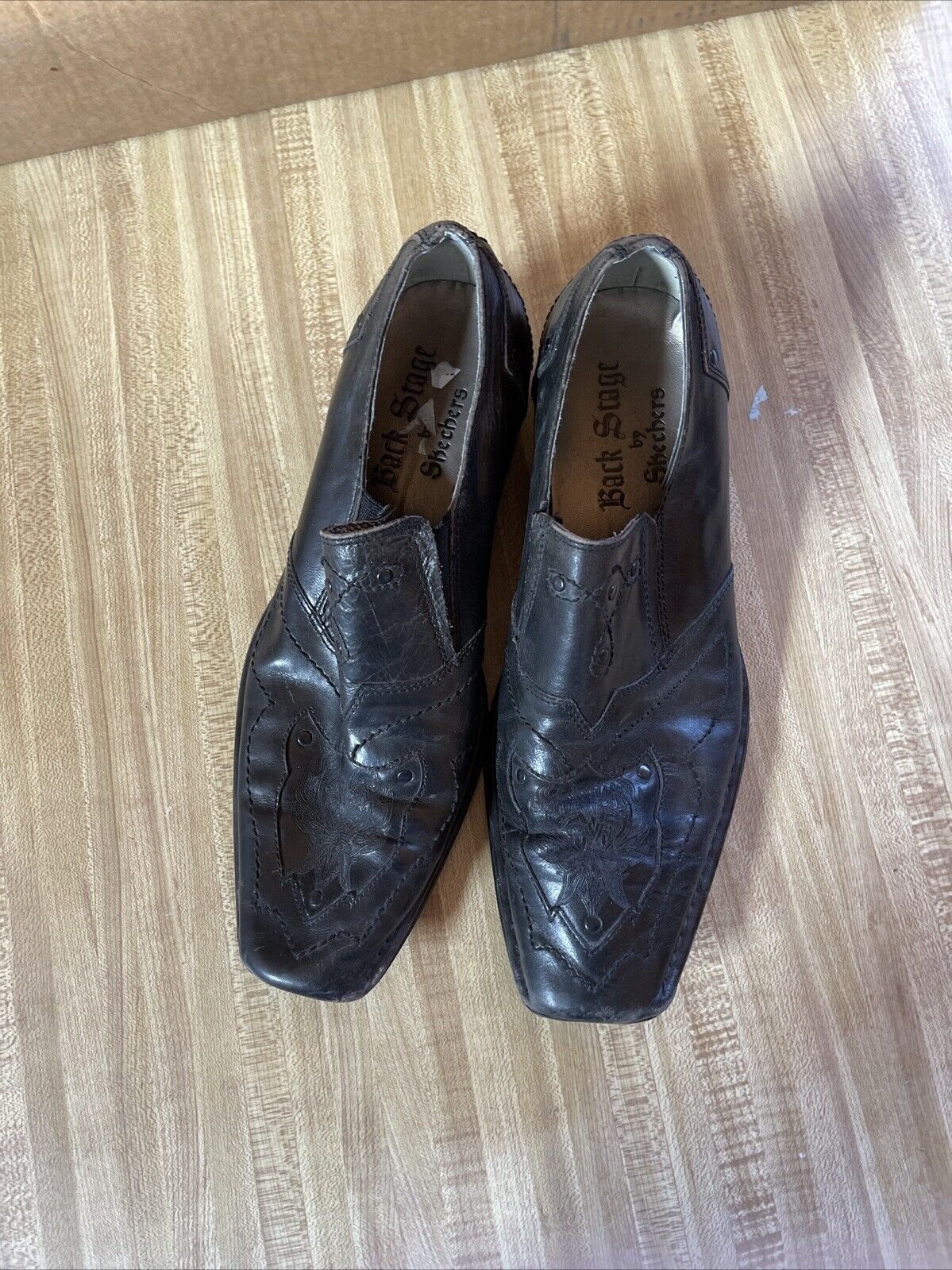 Black leather Back Stage by Skechers shoes with square toe and embossed design on wooden floor