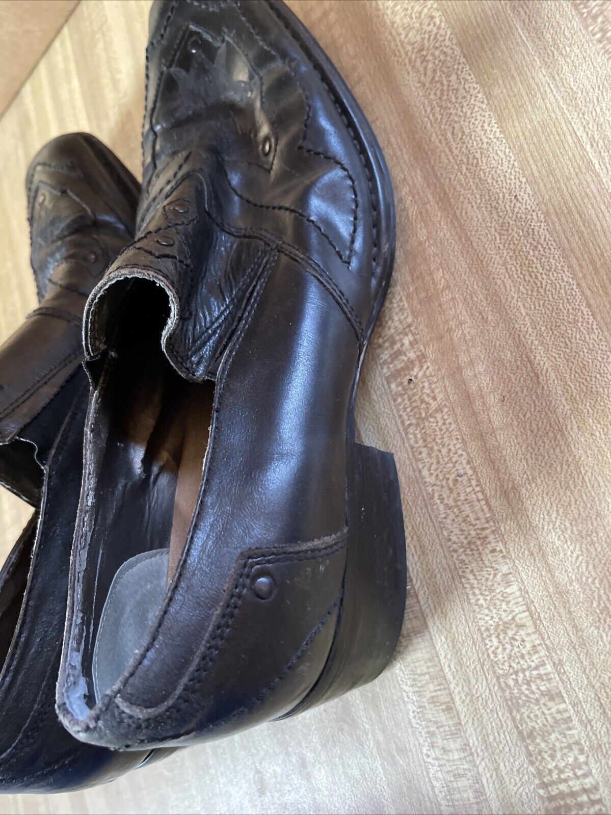 Pair of black leather Back Stage by Skechers shoes with detailed stitching on wooden floor