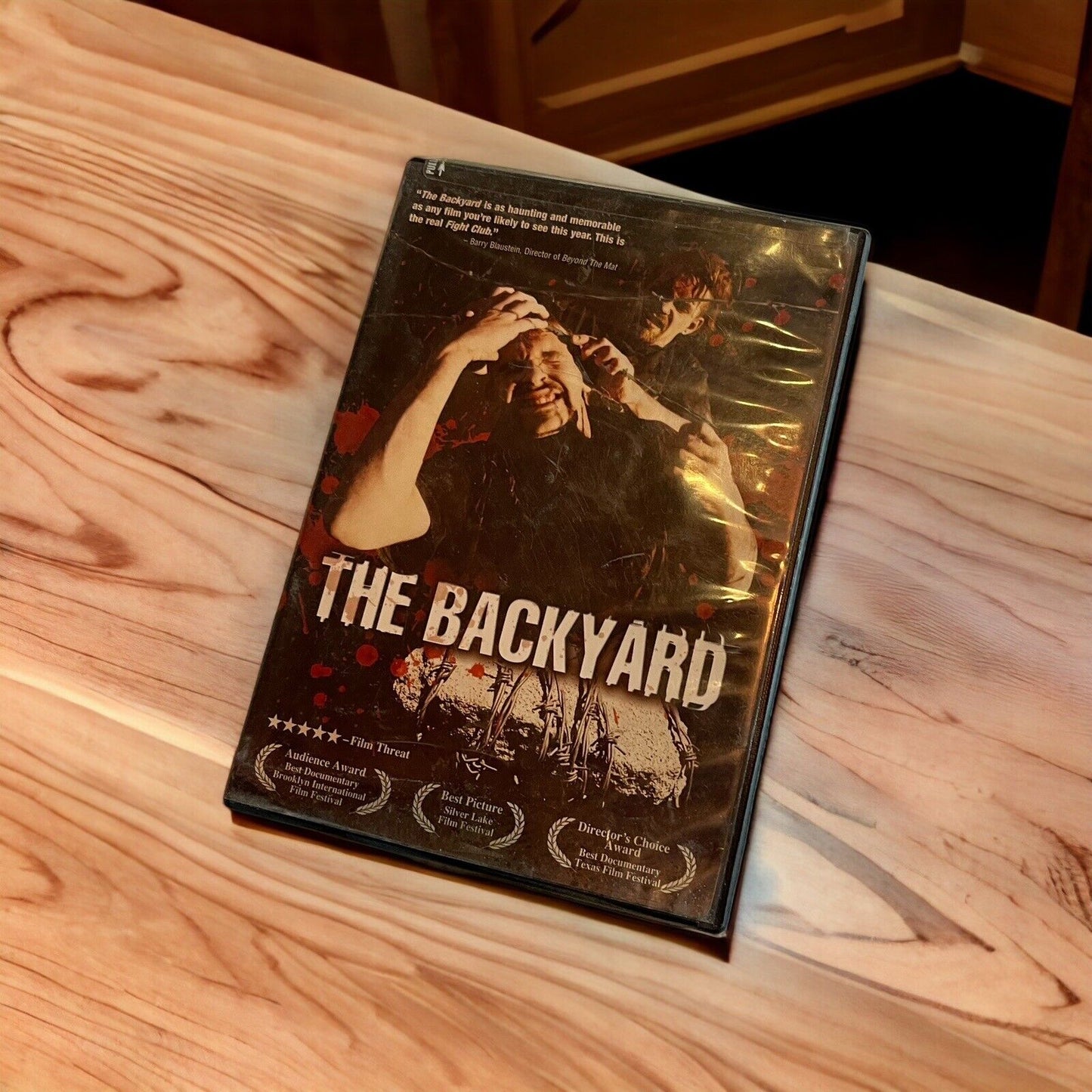 The Backyard DVD 2003 cover featuring characters in a dramatic scene on wooden table