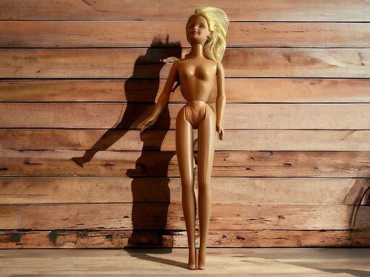 Vintage Barbie doll for sale with blonde hair standing against a wooden background