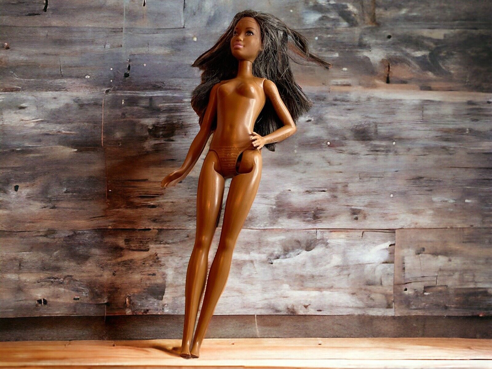 Naked vintage Barbie doll for sale with long brown hair standing against wooden background